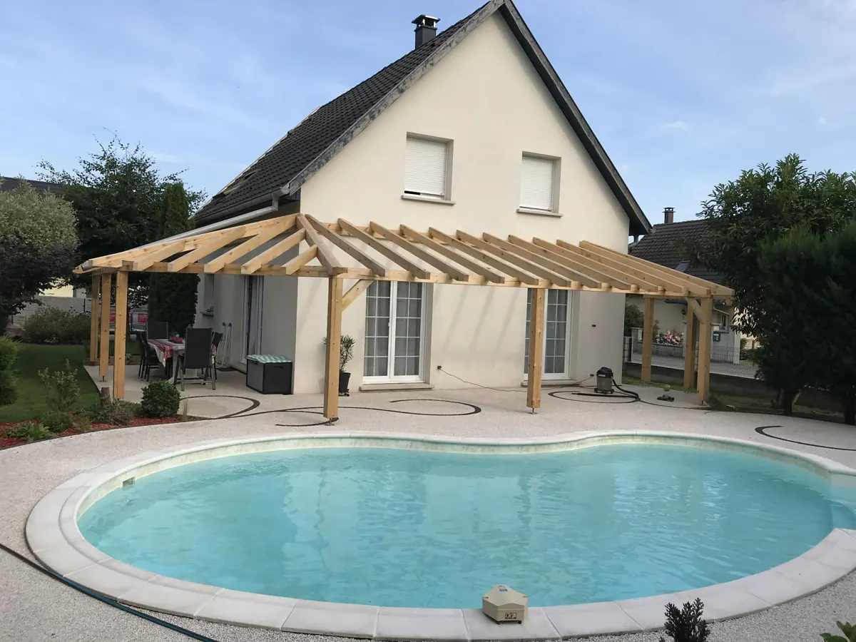 La même pergola en bois terminée, au bord d'une piscine